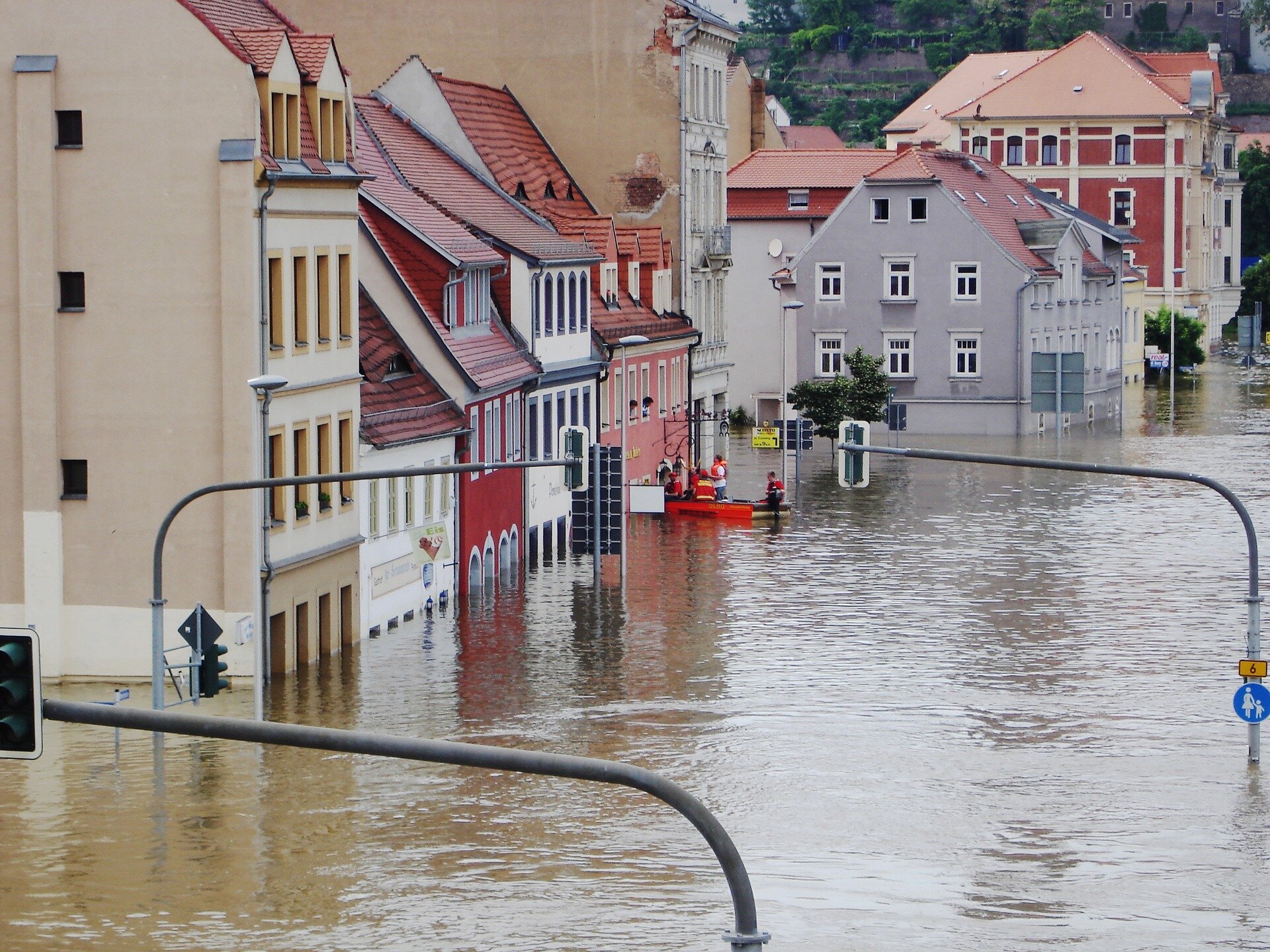Auf dem Bild sieht man Häuser, die im Hochwasser stehen. Im Hintergrund erkennt man ein Rettungsboot an einem Haus. | © LucyKaef / Pixabay