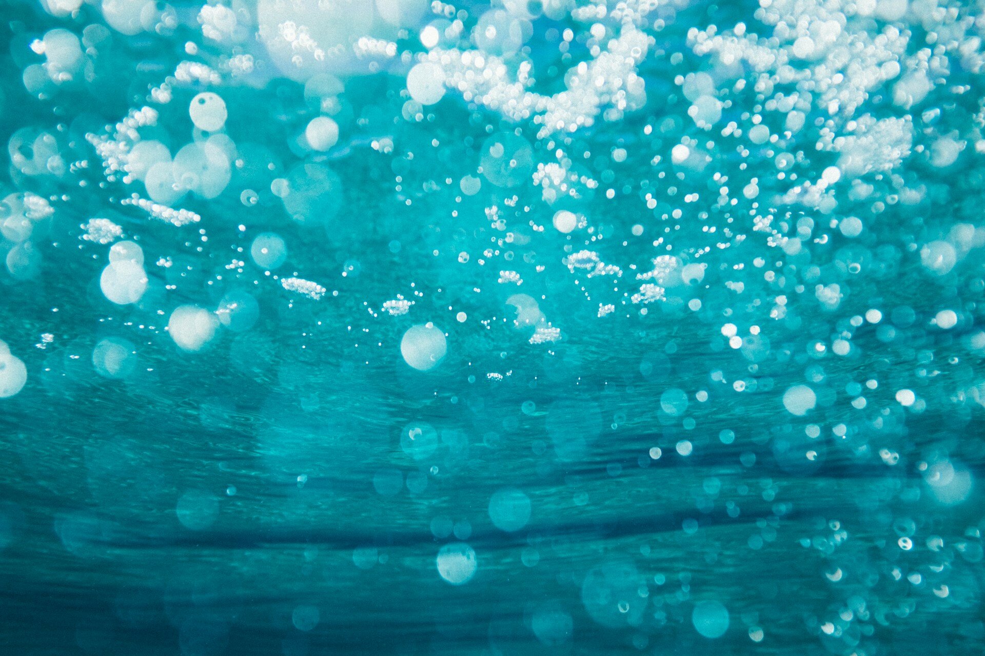 Das Bild zeigt Luftblasen unterhalb der Wasseroberfläche | © Sime Basioli/Unsplash