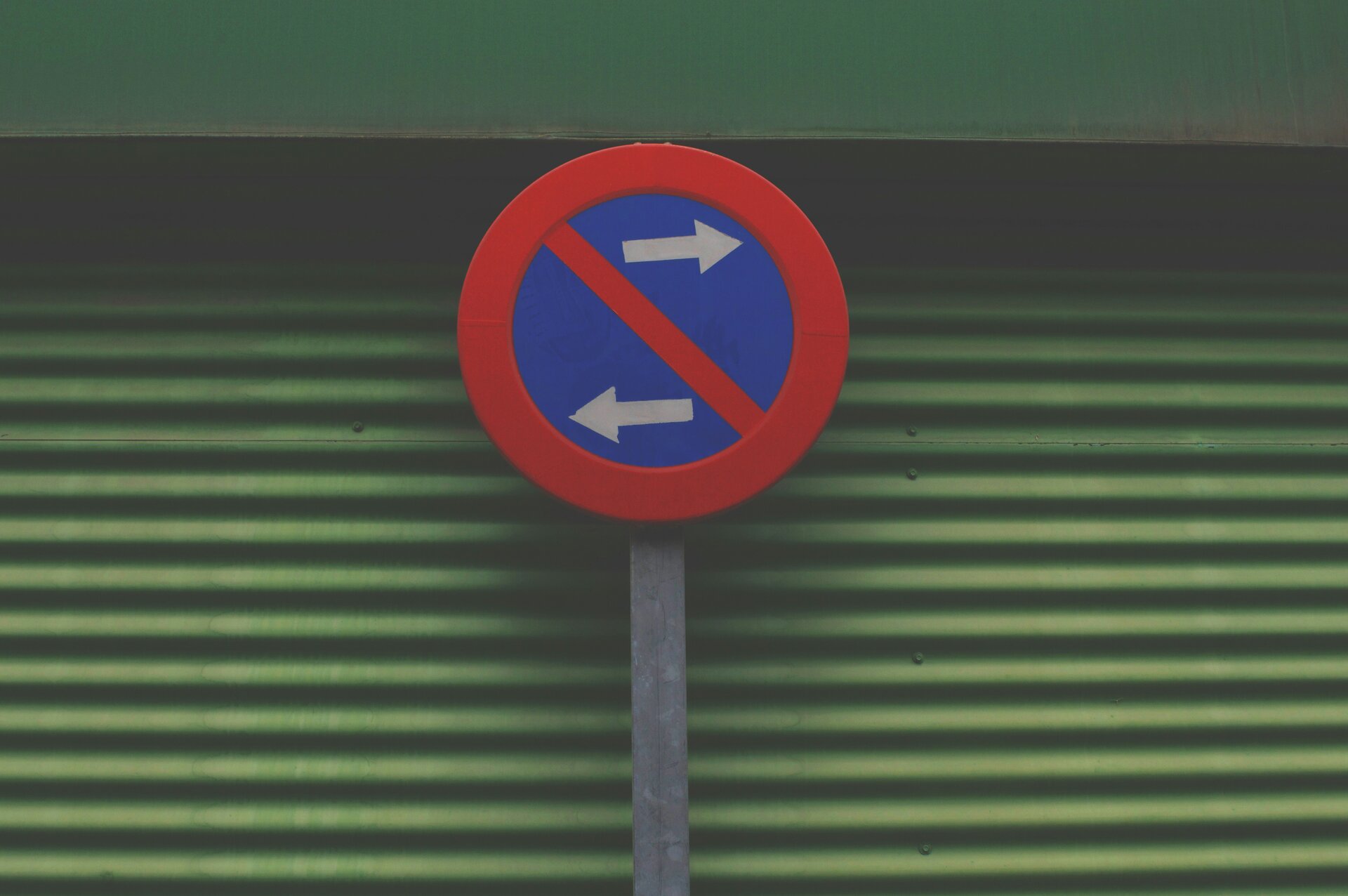 Das Bild zeigt ein "Eingeschränktes Halteverbot"-Schild vor einer grünen gewellten Wand | © Tormius/Unsplash