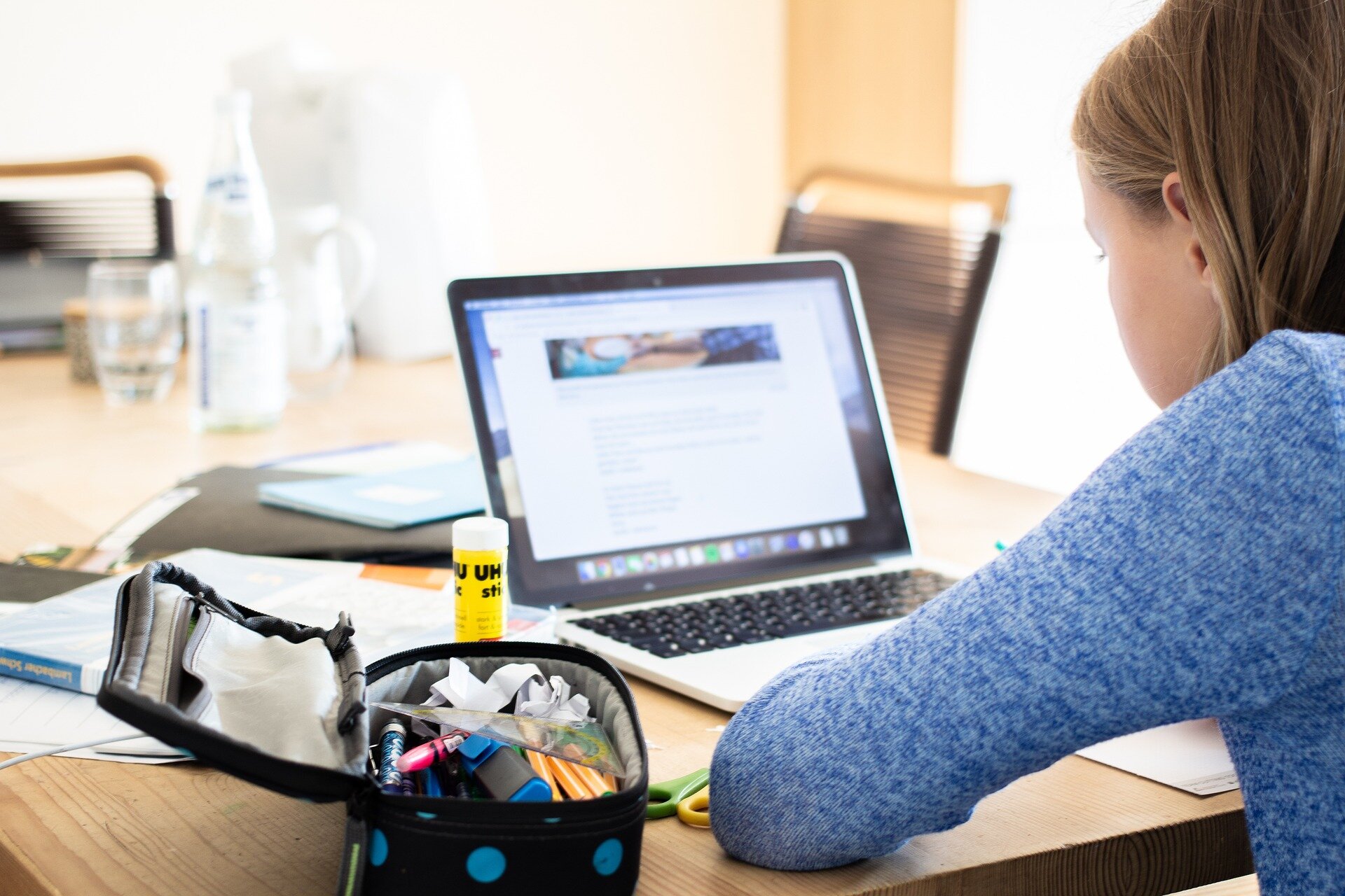 Auf dem Bild sieht man ein Mädchen von der Seite, die vor einem Laptop sitzt. Neben ihr liegt ein geöffnetes Mäppchen mit Stiften und ein Klebestift | © zapCulture / Pixabay