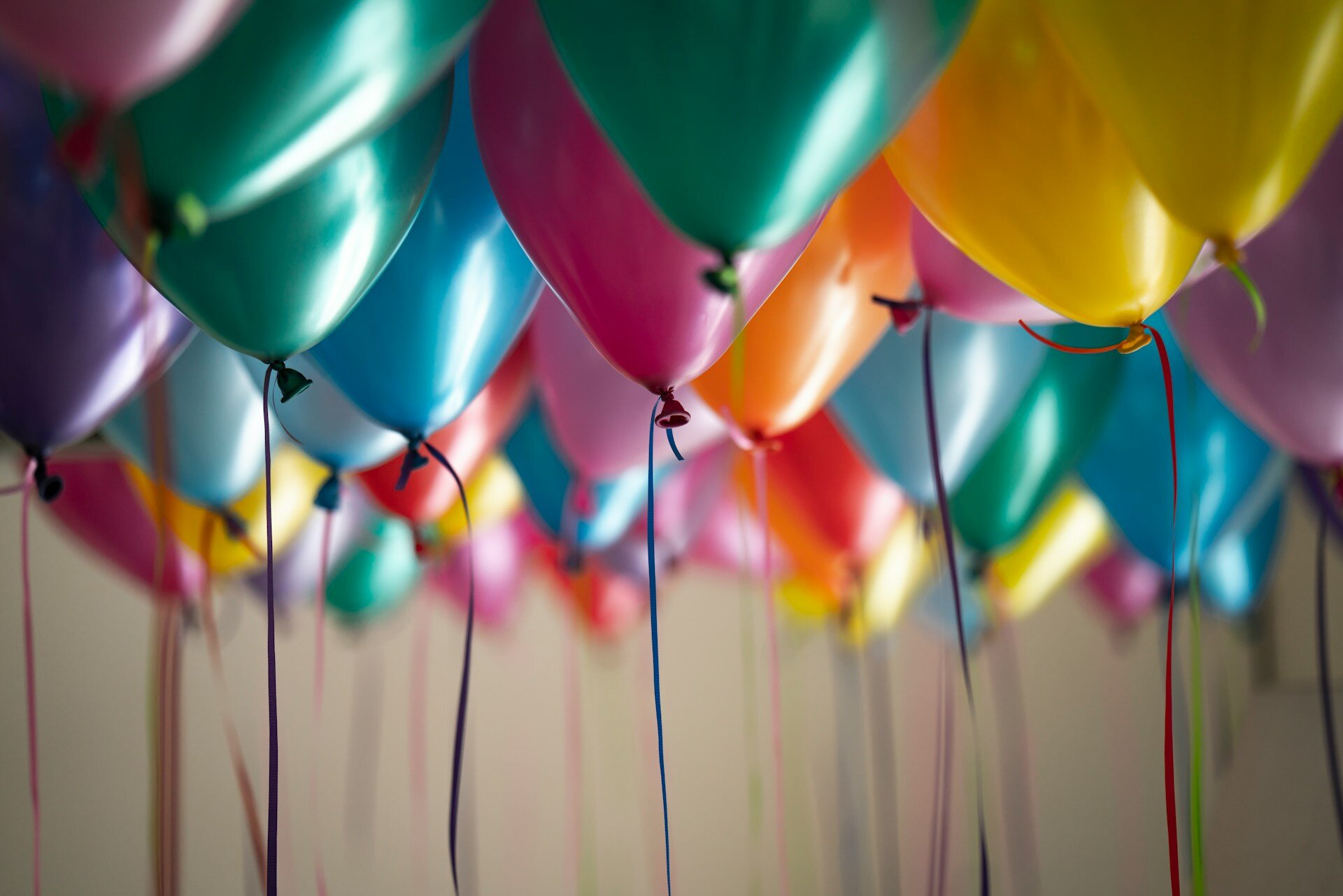 Auf dem Bild sind bunte Heliumballons zu sehen, die unter der Decke schweben und an denen bunte Bänder befestigt sind. | © Adi Goldstein
