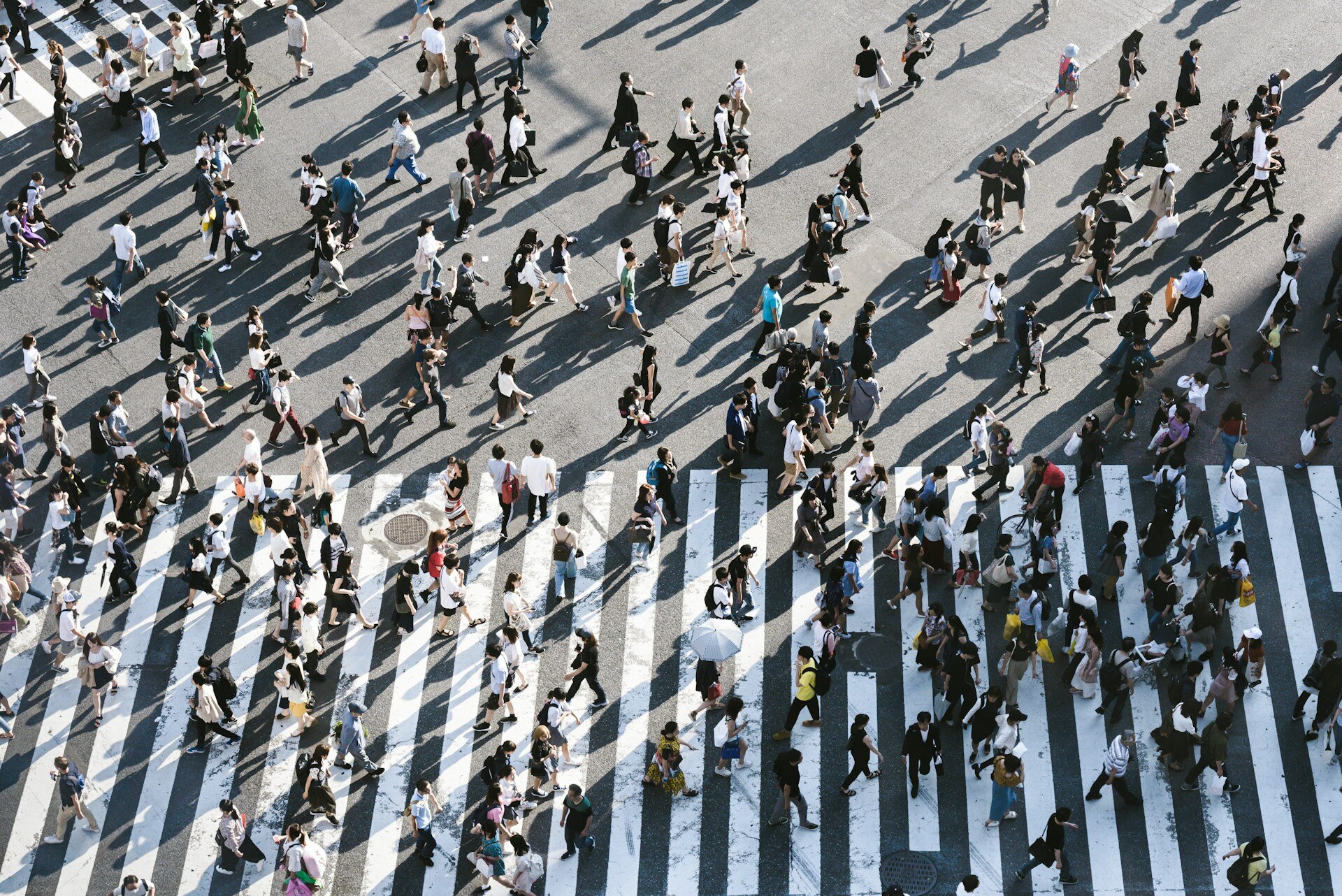 The picture shows a crowd of people crossing a street intersection from above | ©  Ryoji Iwata / Unsplash