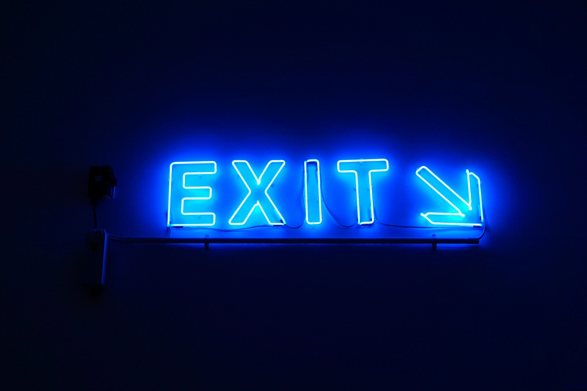 Das Bild zeigt blaue Leuchtbuchstaben, die EXIT und einen Pfeil schräg nach rechts unten zeigen | © Dustin Tramel / Unsplash