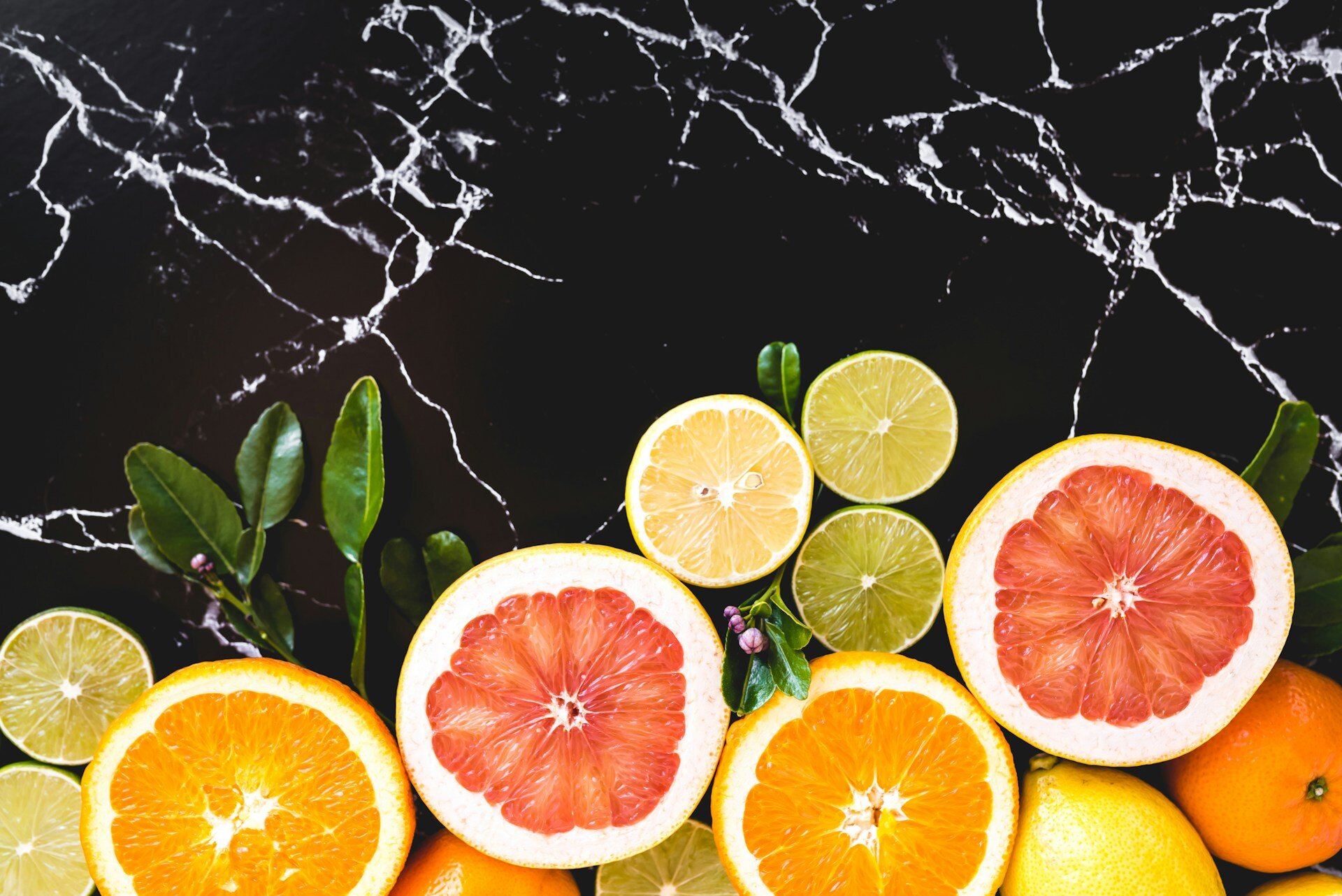 Auf dem Bild sieht man aufgeschnittene Orangen, Zitronen, Limetten und Grapefruit | © Hayley Maxwell / Unsplash