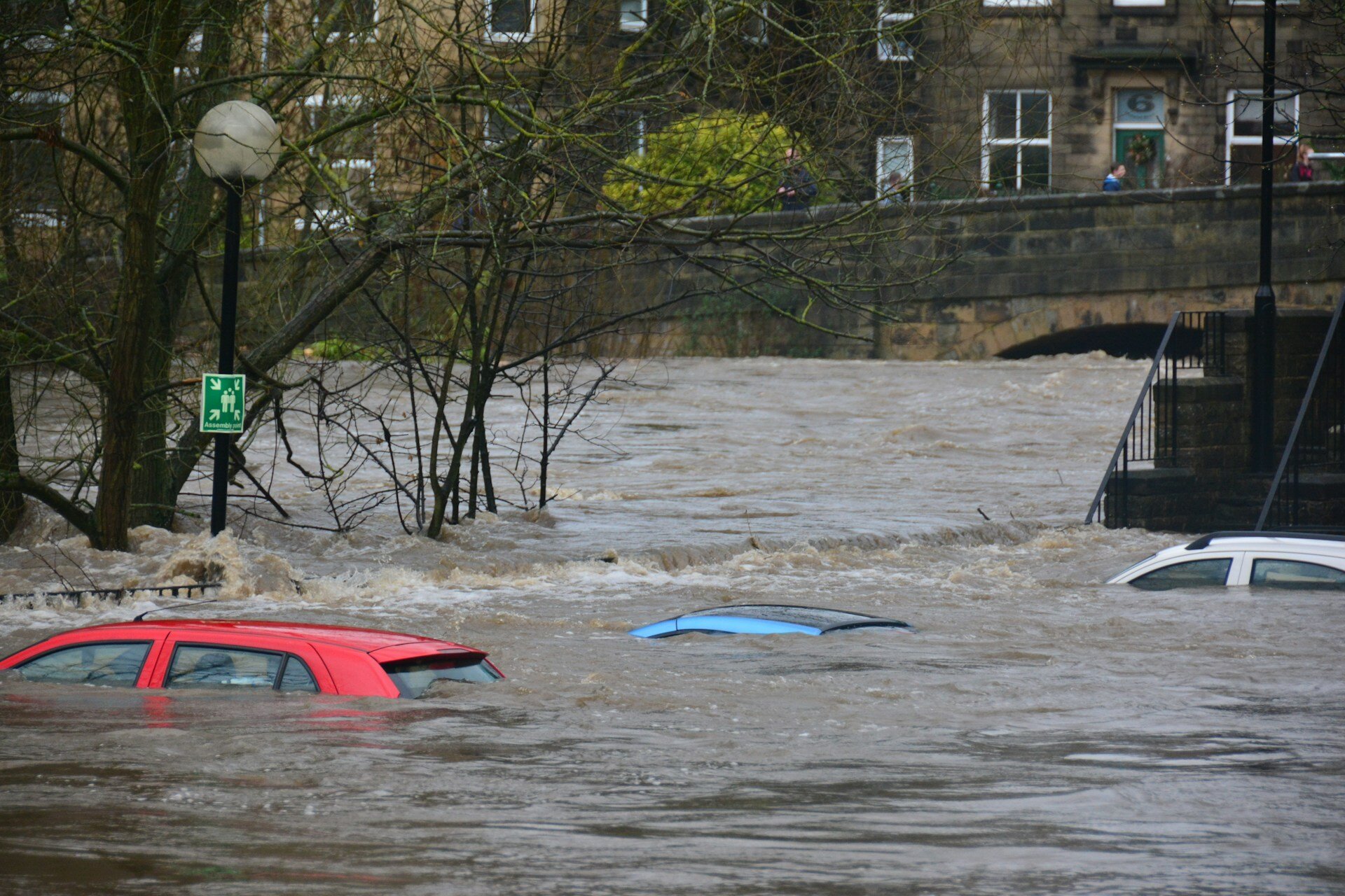 Auf dem Bild sieht man ein rotes, blaues und weißes Auto, von dem jeweils nur noch das Dach aus dem Hochwasser zu sehen ist | © Chris Gallagher / Unsplash