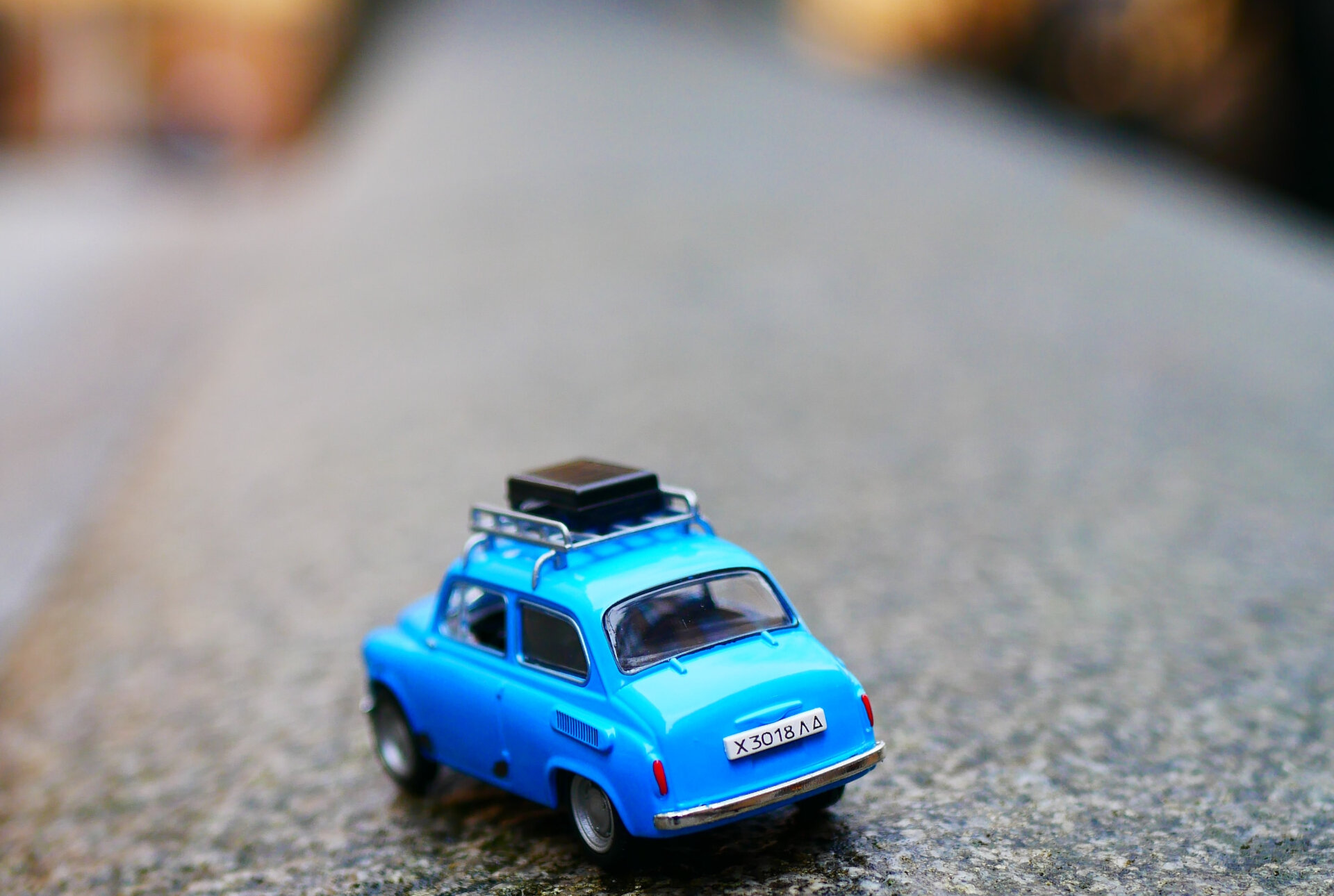 Das Bild zeigt ein kleines blaues Spielzeugauto mit einem Koffer auf dem Dachgepäckträger | © Karine germain / Unsplash