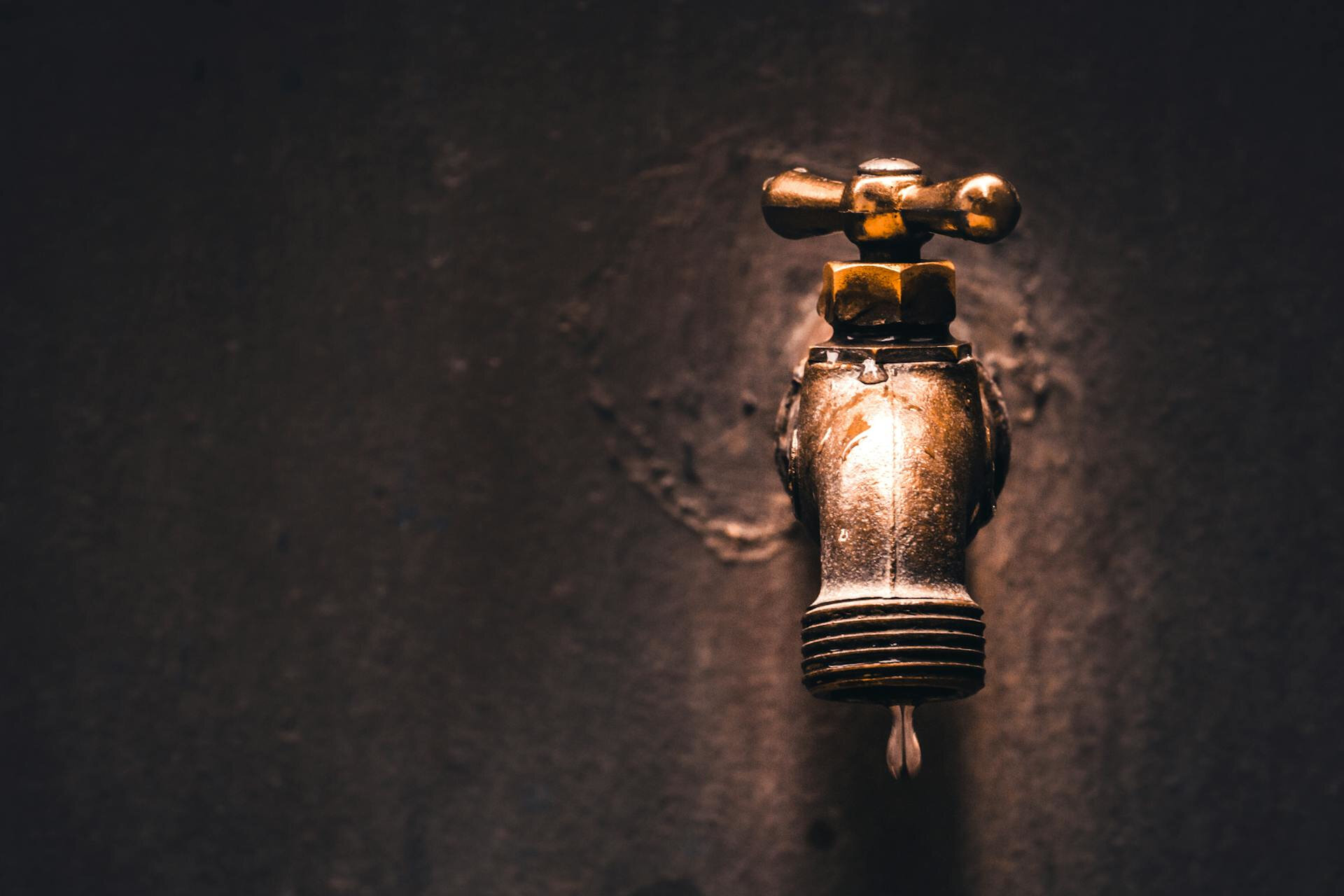 Muss ich das Wasser am Haupthahn abdrehen, bevor ich in den Urlaub fahre? | © RENDAN CATIPAY / Pexels Nahaufnahme eines tropfenden Wasserhahns mit klaren Details und glänzender Oberfläche. | © RENDAN CATIPAY / Pexels