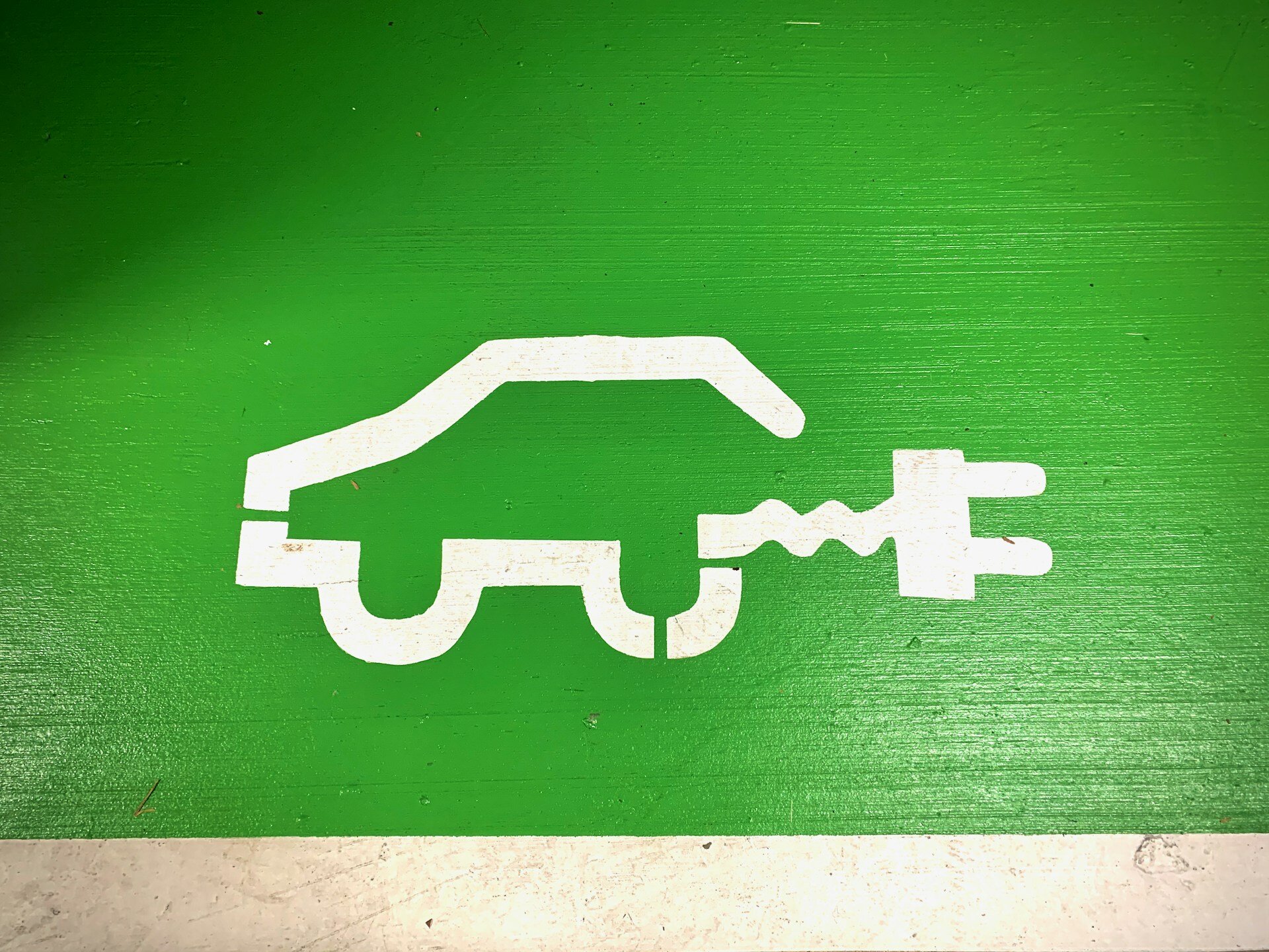 Das Bild zeigt ein auf eine grüne Wand aufgemaltes Auto mit Stecker | © Ralph Hutter/Unsplash