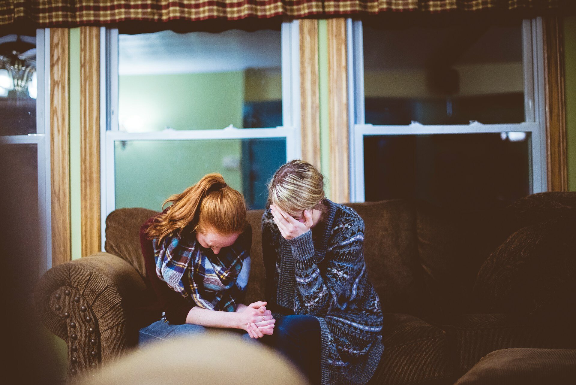 Auf dem Bild sieht man zwei Frauen auf dem Sofa sitzend, die sich die Hände aus Verzweiflung vor das Gesicht halten | © Ben White/Unsplash