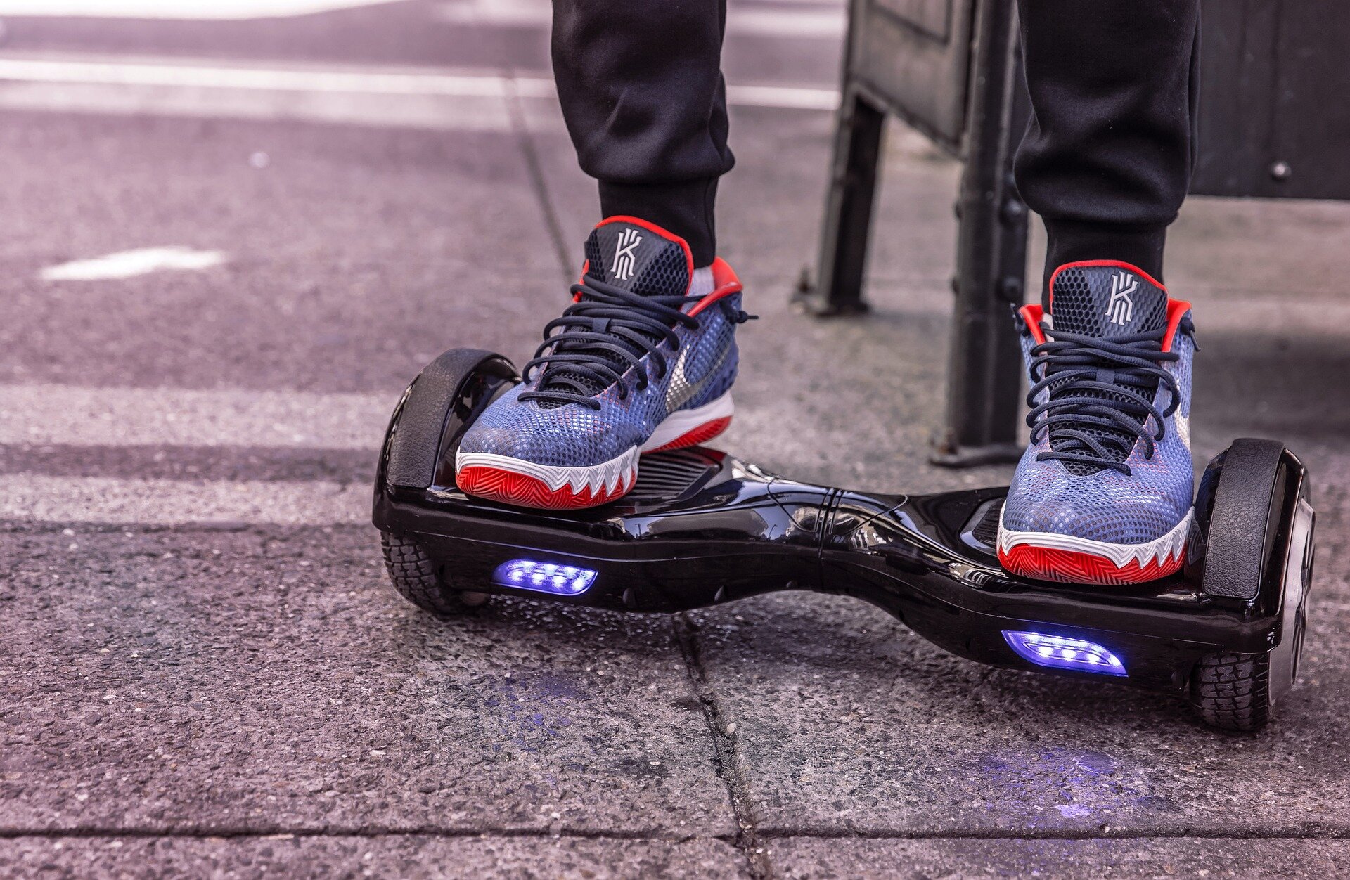 Auf dem Foto sieht man einen Ausschnitt einer Person ab den Beinen, die auf einem Hoverboard steht. Die Person trägt blau violett-farbene Sneaker mit roter Sohle. | © Schäferle / Pixabay